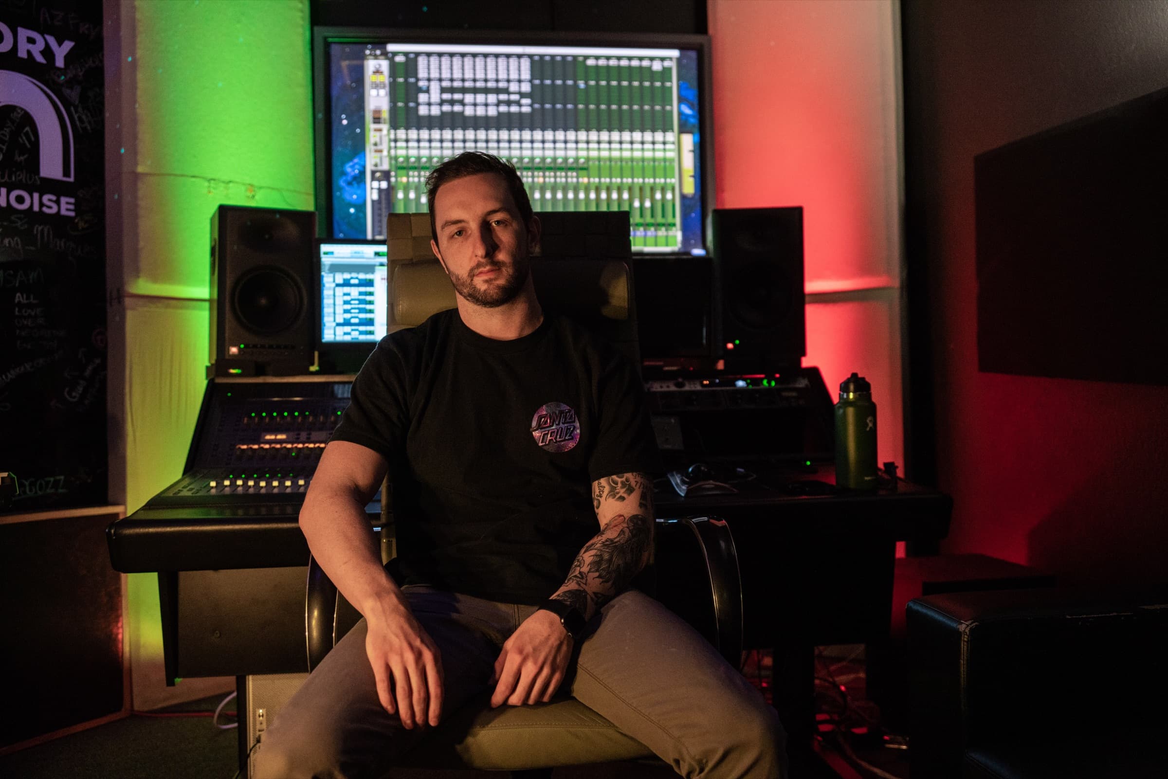 Dylan sitting at the mixing console in a studio lit green and red